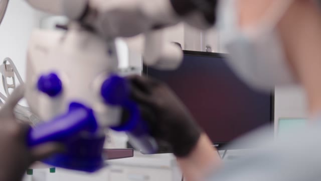 Врач работает со стоматологическим микроскопом